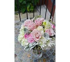 a vase filled with pink and white flowers sitting on top of a table next to a fence