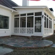 a white house with screened porch and stone patio