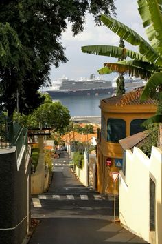 a narrow street leading to a cruise ship in the distance