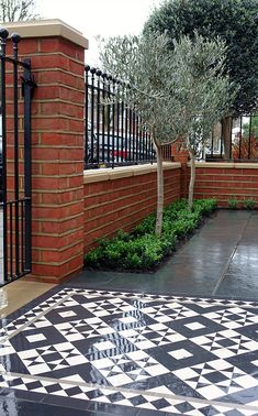 a black and white checkered tile floor in front of a brick building with an olive tree