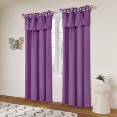 a living room with purple curtains and a white rug