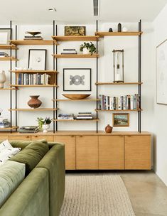 a living room filled with furniture and bookshelves next to a wall covered in pictures