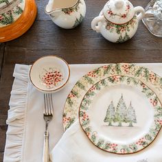 the place setting is set with dishes, cups and utensils for christmas dinner