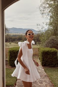 a woman wearing sunglasses and a white dress