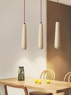 three hanging lights above a wooden table with chairs and lemons on the table in front of it