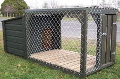 a dog house made out of wood and wire with a door open on the grass