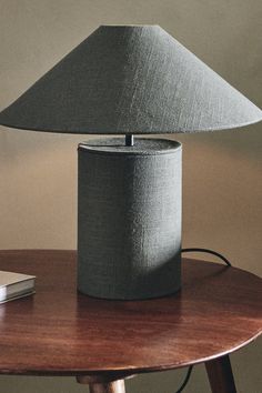 a table lamp sitting on top of a wooden table next to a book and remote control