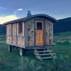 a small wooden cabin sitting in the middle of a field with steps leading up to it