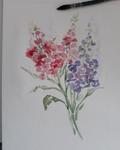 a watercolor painting of some flowers on a white paper with a black marker next to it