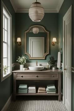 a bathroom with green walls and a large mirror on the wall above the sink, along with several folded towels