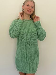 a woman in a green sweater posing for the camera with her hands on her hips