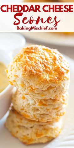 cheddar cheese scones are stacked on top of each other with a bowl of soup in the background