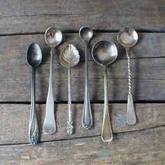 six spoons are lined up on a wooden table