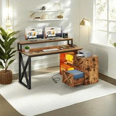 a computer desk with two monitors and a keyboard on it in front of a potted plant