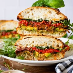 two sandwiches stacked on top of each other with lettuce and tomato toppings