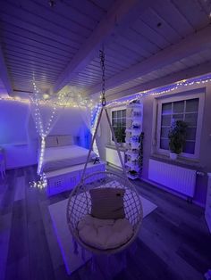 a bedroom with purple lighting and a hanging chair in the middle of the room is lit up by string lights