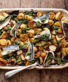 a casserole dish with fish, potatoes and broccoli in it on a wooden table