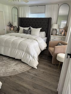 a large white bed sitting in a bedroom on top of a hard wood flooring