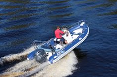 two people riding on the back of a blue and white boat