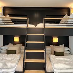 bunk beds with stairs leading up to them in a room that has black walls and white bedding