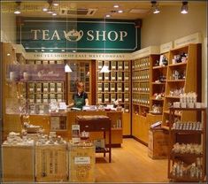 a store front with the words tea shop on it's glass door and shelves full of items