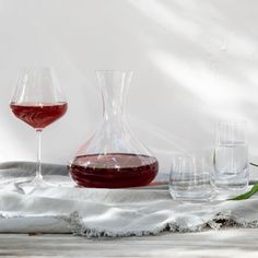 a table topped with wine glasses and a decanter filled with liquid next to each other