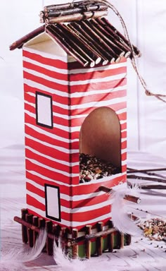 a red and white striped birdhouse with sticks sticking out of it