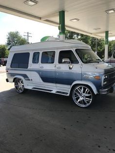 a white and blue van parked at a gas station