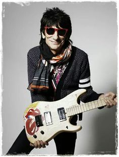 a man in sunglasses and scarf holding an electric guitar with tongue decorations on its body