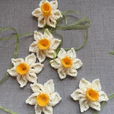 crocheted flowers with yellow centers on a gray background, arranged in the shape of four petals