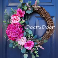 a purple wreath with pink flowers and greenery on a blue door that says door2doorn