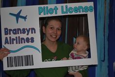 a woman holding up a sign that says pilot license with a baby in her lap