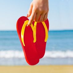 a pair of flip flops with a hot dog on them are held up by a person's hand