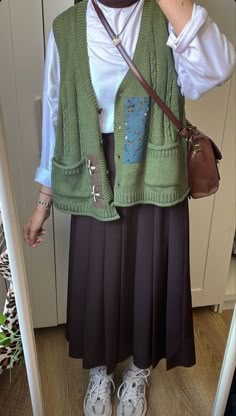 a woman wearing a green vest and skirt