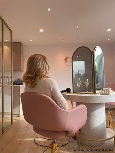 a woman sitting in a pink chair at a counter