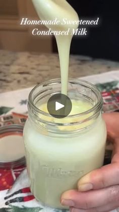 someone is pouring milk into a glass jar