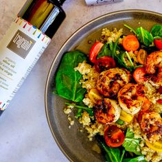 a plate full of shrimp and vegetables next to a bottle of olive oil on a table