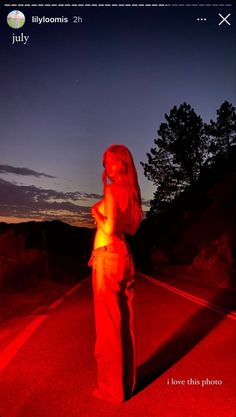 a woman standing in the middle of a road with red light on her chest and arms