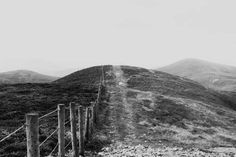 a black and white photo of a fence on the side of a mountain