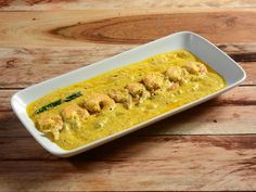 a white plate topped with food on top of a wooden table covered in green sauce