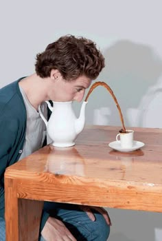 a man sitting at a wooden table with a teapot on it