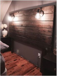 a bed with wooden headboard and two lights on the wall next to each other