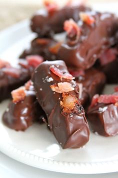 chocolate covered donuts with bacon on top sit on a white plate, ready to be eaten