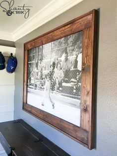 an old photo hangs on the wall next to a wooden bench in a baseball dugout