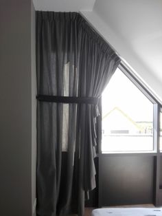 an open window in a room with curtains on the windowsill and a bed next to it