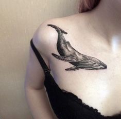 a woman wearing a black top with a whale tattoo on her chest