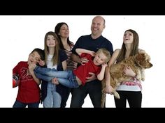 a group of people standing next to each other with a dog on their lap and two children holding them