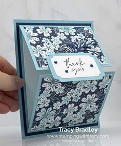 a hand holding up a thank you card with blue and white floral designs on it