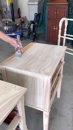 a person sanding wood on top of a wooden table in a room with other furniture