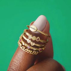 a woman's hand holding a stack of rings with the word mom written on it